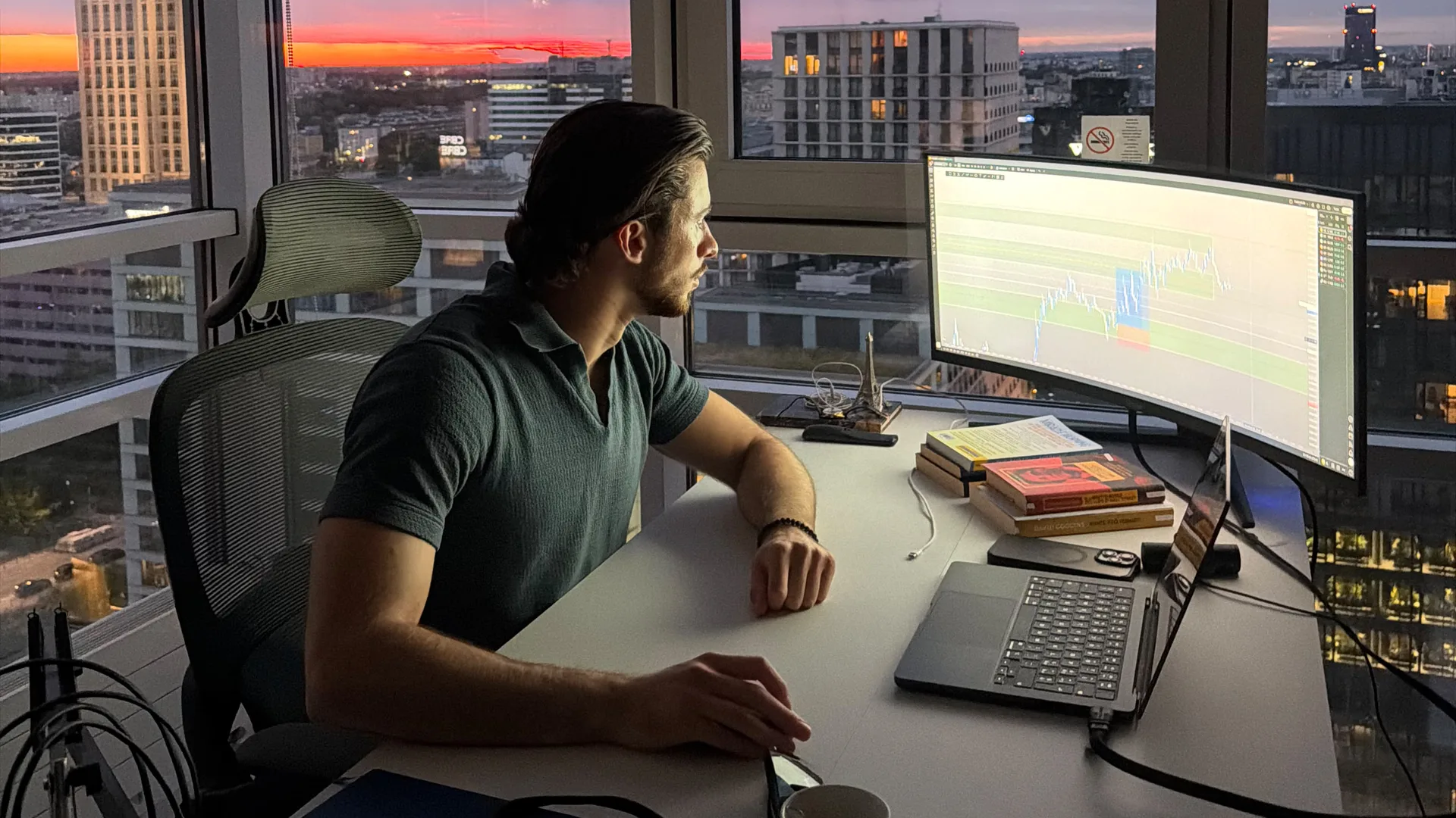 Nick Parodi al desk davanti ai grafici dei mercati al tramonto